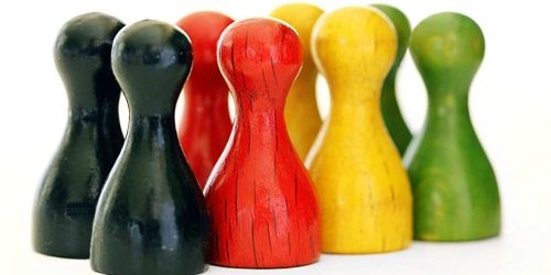 Spielfiguren aus Holz in den Farben schwarz, rot, gelb und grün