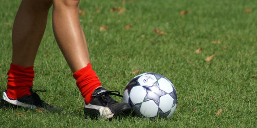 Beine eines Fußballspielers mit Ball