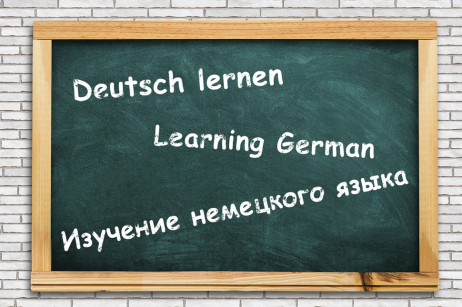 Auf einer Tafel steht der Text "Deutsch lernen" in deutsch, englisch und russisch