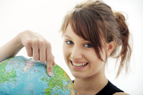 Teenagerin zeigt mit dem Finger auf einen Globus