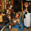 Bernhardusfest. Ein Ritter wird auf einem Strohballen verarztet. Ein Geistlicher steht neben ihm und betet.
