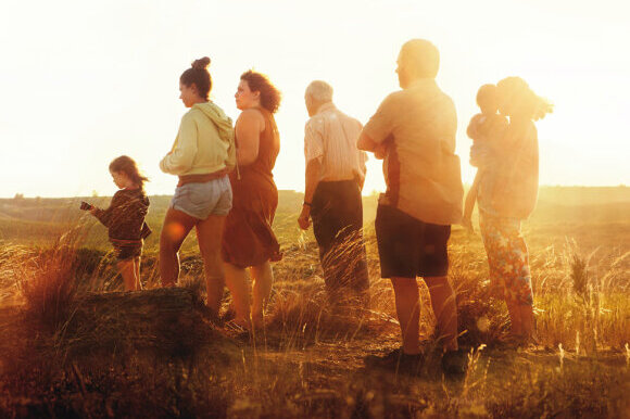 Filmplakat: Eine Gruppe Menschen unterschiedlichen Alters steht auf einem Feld. Text: " Alcarras; die letzte Ernte".