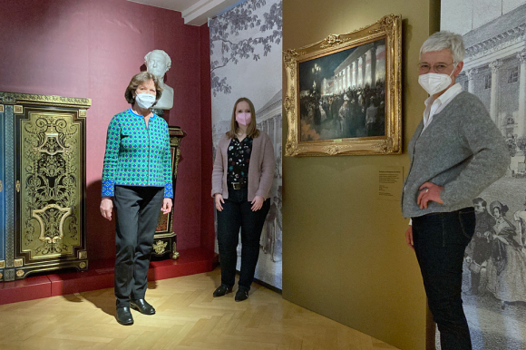 OB Margret Mergen, Dr. Katja Mikolajczak und Restauratorin Gloria Benner (von links) vor dem restaurierten Gemälde „Kurhaus und Kurgarten bei Nacht“, das Friedrich Stahl um 1890 fertigte. 