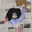 Bild von einer Frau, die durch ein Loch einer Zeitung schaut und ein Schild mit der Aufschrift "Jetzt sind wir dran" in die Luft streckt
