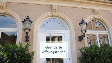 Eingang Rathaus mit Schild: Geänderte Öffnungszeiten.