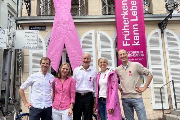 Gruppenbild vor den rosafarbenen Schleifen am Rathaus