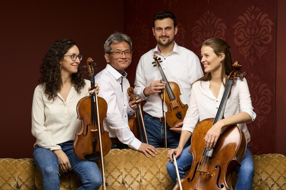 Gruppenfoto von vier Musikern und ihren Instrumenten.