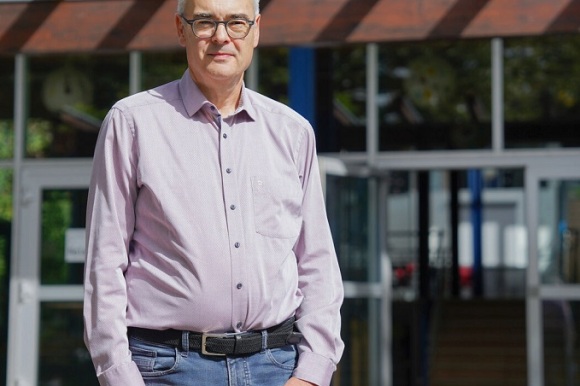 Der neue Schulleiter steht vor dem Schulgebäude. 