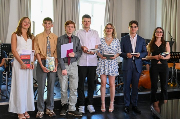 Die Fachpreisträger des Gymnasiums Hohenbaden (von links nach rechts): Lavinia Paul, Valerian Straß, Luca Mürb, Samuel Niemz, Anna Alokhina, Daniil Wenzel und Clara Trapp stehen auf einer Bühne mit Urkunden und Preisen in den Händen. 