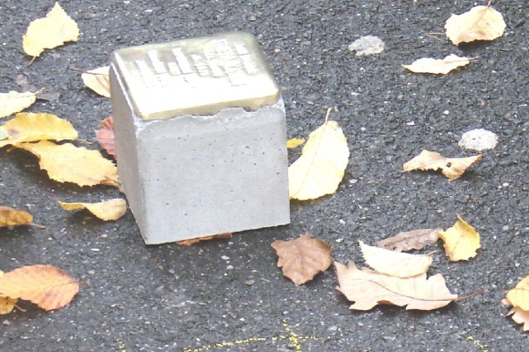 Ein Stolperstein liegt auf der Straße.
