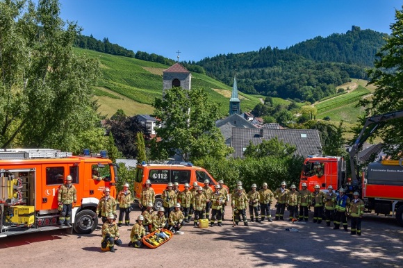 Gruppenbild der Mitglieder der Feuerwehr Neuweier mit ihren Einsatzfahrzeugen.