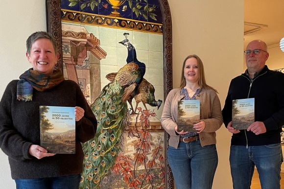 3 Menschen halten ein Buch in ihren Händen.