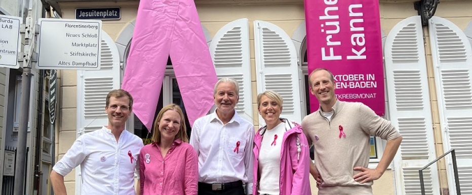 Gruppenbild vor den rosafarbenen Schleifen am Rathaus