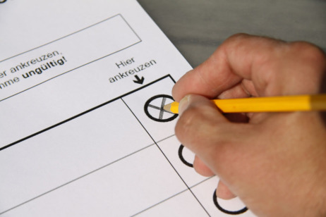 Hand mit Stift kreuzt einen Wahlschein an
