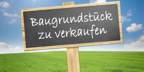 Schild auf einer Wiese auf dem geschrieben steht: "Baugrundstück zu verkaufen"