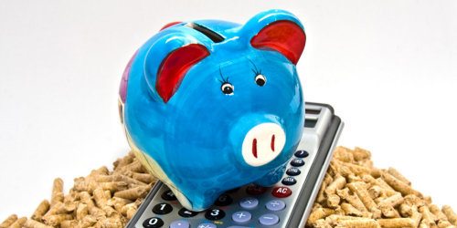 Ein blaues Sparschwein und ein Taschenrechner stehen auf einem Haufen Holzpallets