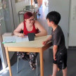 FSJ bei der Mittagstischbetreuung der Theodor-Heuss-Schule: Eine junge Frau sitzt an einem kleinen Tisch und spricht mit einem Jungen