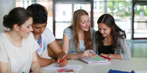 Vier Schüler sitzen an einem Tisch und lernen gemeinsam
