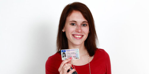 Eine Frau hebt einen Führerschein und einen Autoschlüssel in der Hand