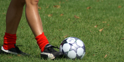 Beine eines Fußballspielers mit Ball