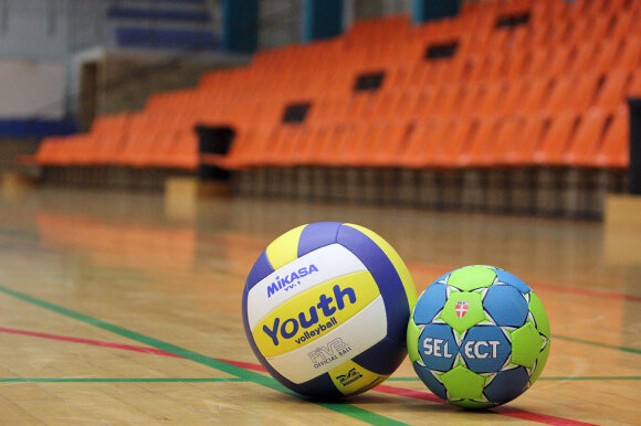 Volleyball und Handball liegen auf dem Boden einer Sporthalle