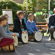 Kinder und Lehrer der Musikschule spielen auf Trommeln