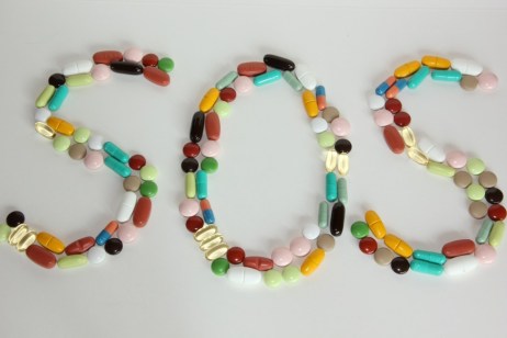 Aus verschiedenen bunten Tabletten ist das Wort S O S gelegt.