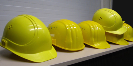 mehrere gelbe Arbeitsschutzhelme in einer Reihe