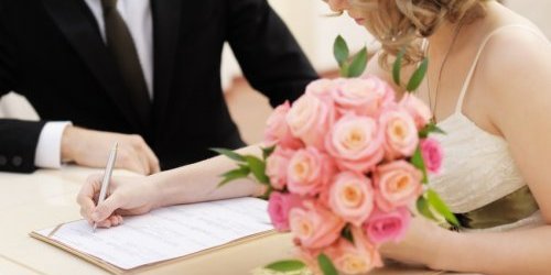 Hand der Braut, unterschreibt beim Standesamt die Urkunde