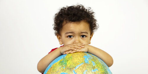 Ein kleiner Junge der sich auf einem Globus abstützt