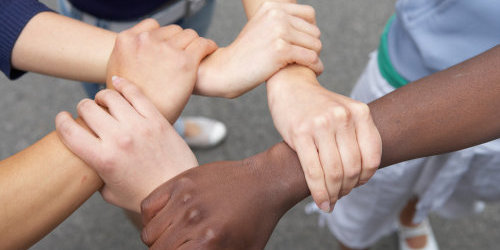 Hände von Menschen verschiedener Herkunft greifen ineinander