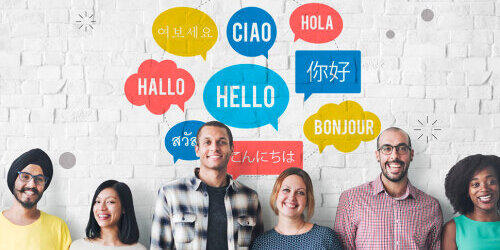 Sechs Personen mit unterschiedlicher Nationalität stehen in einer Reihe an einer Wand. Über ihnen mehrere Sprechblasen in denen das Wort "Hallo" in verschiedenen Sprachen steht.