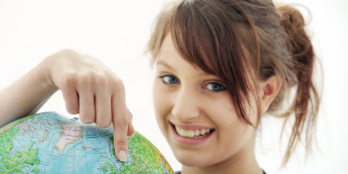 Teenagerin zeigt mit dem Finger auf einen Globus