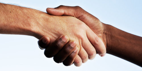 Handschlag einer weißen und einer Afroamerikanischen Hand