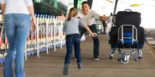Szene am Bahnhof: Im Vordergrund eine Frau von hinten. Ein Kind rennt auf ihren Vater zu der sie mit offenen Armen erwartet.