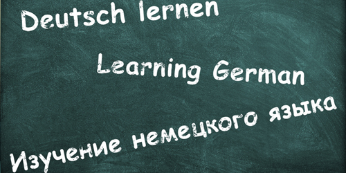 Auf einer Tafel steht der Text "Deutsch lernen" in Deutsch, Englisch und Russisch