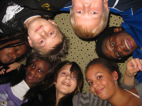 Kinder verschiedener Herkunft und Hautfarbe in einem Kreis - von unten in die Kamera blickend