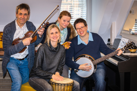 Mitarbeiterinnen und Mitarbeiter der Musikbibliothek halten verschiedene Instrumente.