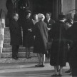 Mehrere Menschen stehen in Schwarz gekleidet vor und auf den Stufen einer Kirche