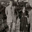 Otto Flake auf einem Weg mit zwei weiteren Personen, einer Frau und einem Mann. Im Hintergrund sind Häuser zu sehen.
