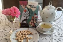 Ein Teeservice auf einer Tischdecke, mit Blume und Buch.