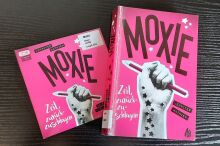 Pinke Covers von Moxie als CD und als Buch. Eine Faust umklammert einen Bleistift.