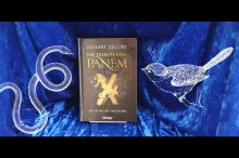 Buchcover "Tribute von Panem" vor blauem Hintergrund eingerahmt von einem Vogel und einer Schlange (Zeichnung)