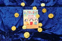 Ein Buch auf blauem Samt. Rundherum Smileys mit verschiedenen Gesichtsausdrücken.