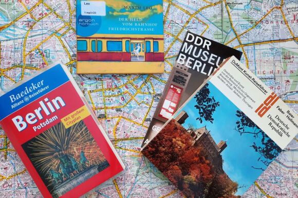 Bücher über Berlin liegen auf aufgebreitetem Stadtplan.