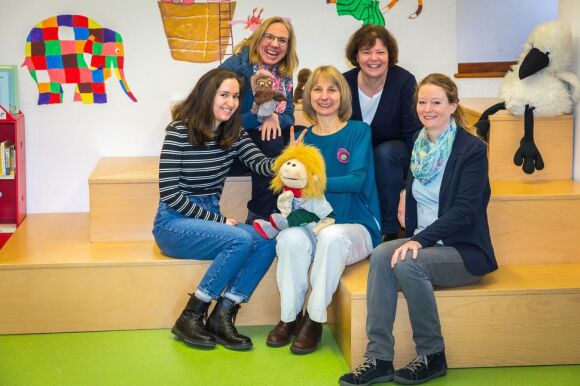Fünf Mitarbeiterinnen der Stadtbibliothek Baden-Baden posieren auf einer Lesetreppe der Kinderbibliothek.