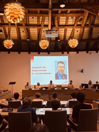 Im Gemeinderatssaal sitzt Bürgermeister Dr. Tobias Krammerbauer vor Schülern.