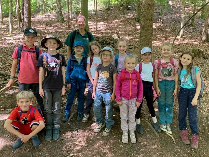 Kinder und eine Erwachsene stehen im Wald. 