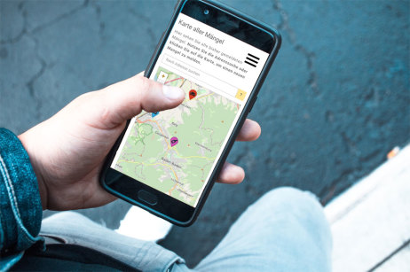 Mann mit Smartphone auf dem die Mängelmelder-App läuft Mann mit Smartphone auf dem die Mängelmelder-App läuft