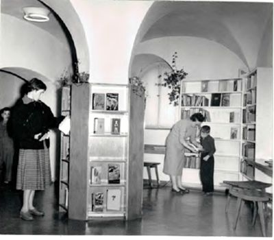 Historisches Foto: Ausleihraum mit Regalen und Personen einer Stadtbibliothek.